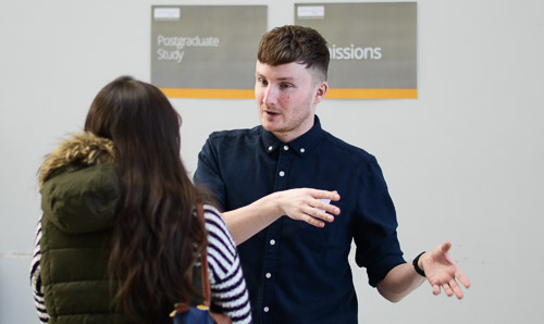 A man speaks with a woman at an event