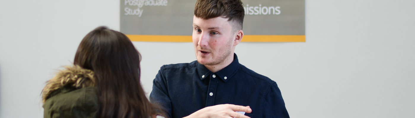 A man speaks with a woman at an event