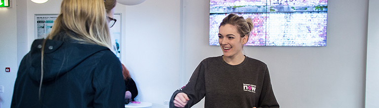 Grey-jumpered student smiling at an indoor charity event