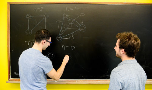 Two students working on a blackboard