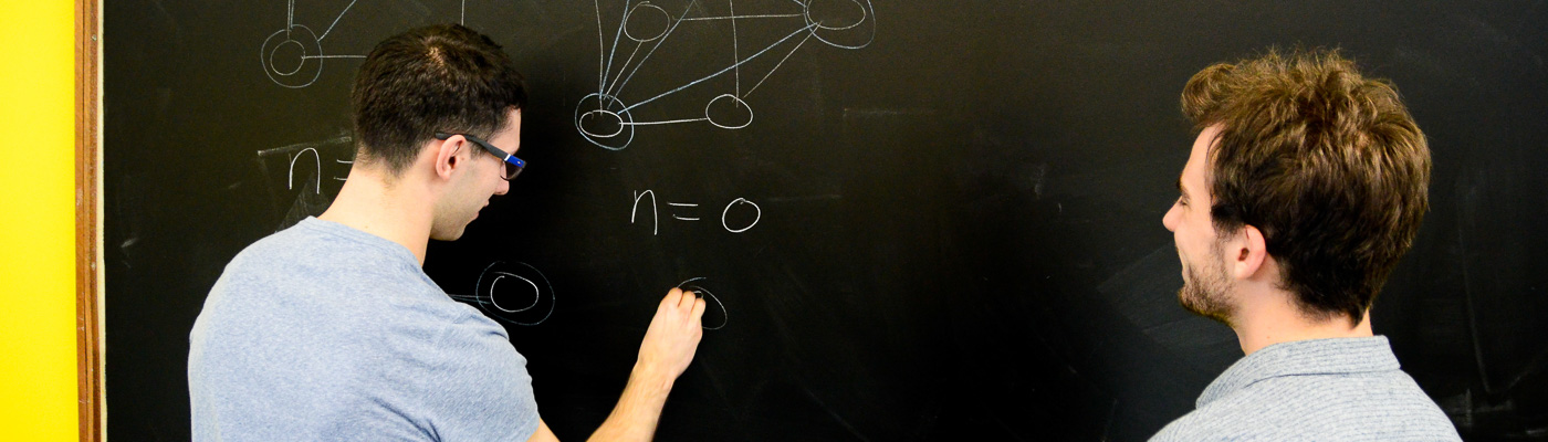 Two students working on a blackboard