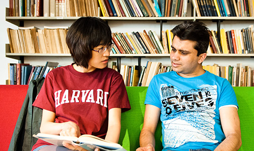 Two students sat in front of shelves of colourful books