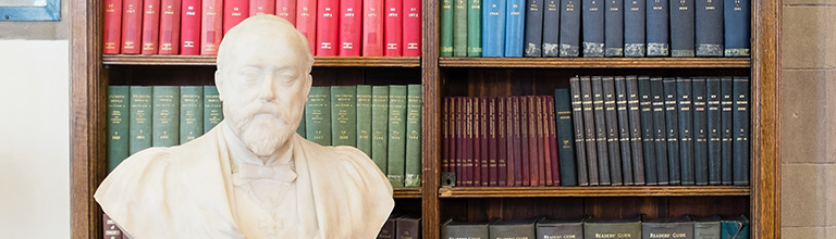 A bust in front of rows of different coloured books