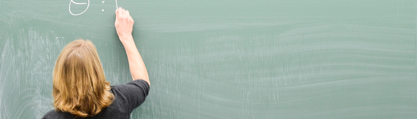 A teacher writing an equation on a blackboard